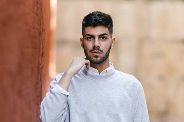 Man wearing a light grey crewneck sweater over a white Oxford shirt