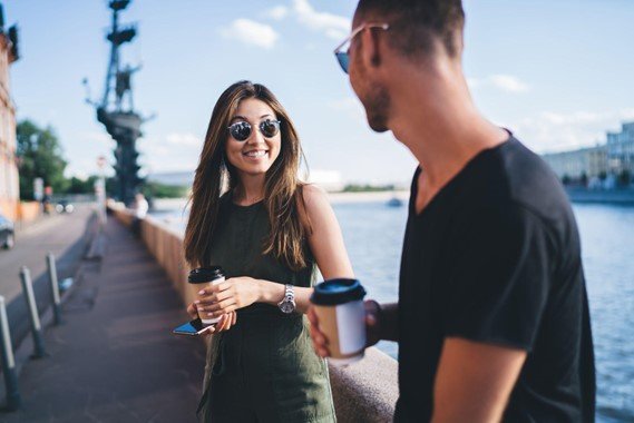 Man and woman laughing together during a conversation outside near water