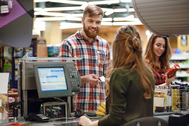Man smiling with female grocery store clerk at checkout
