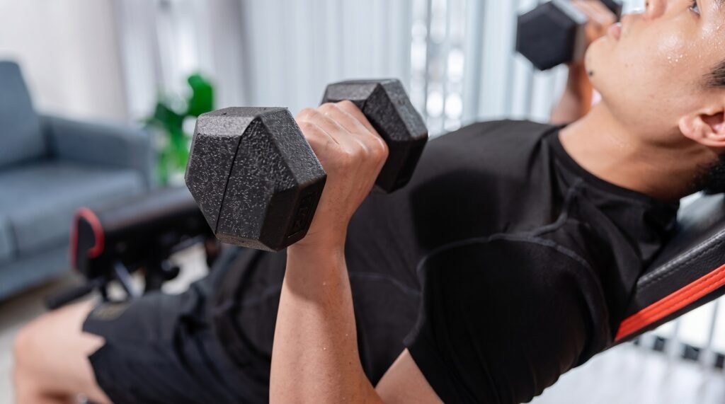 Close-up of two dumbbells lowered below chest level at the bottom of a press