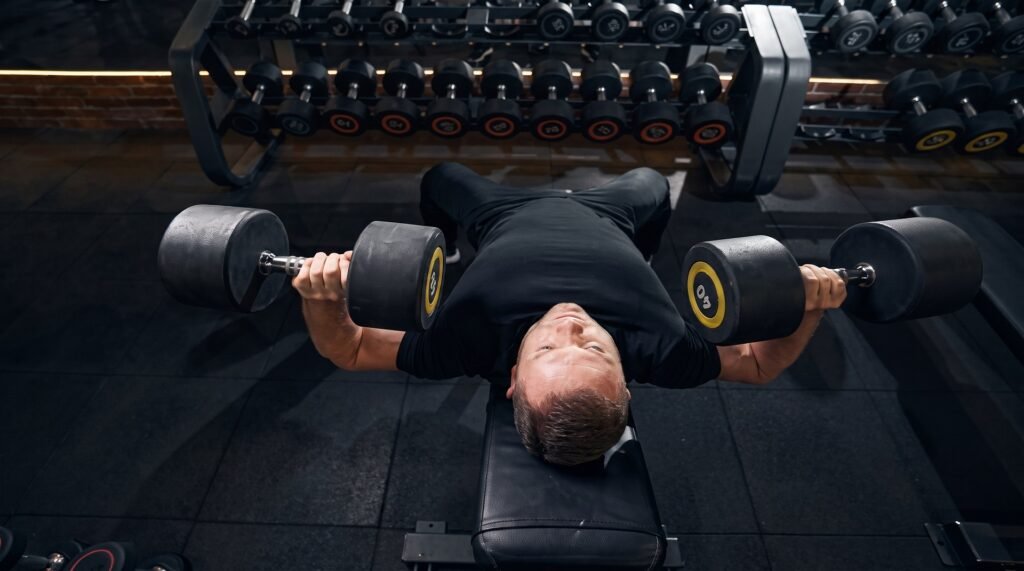 Man performing a flat dumbbell bench press with his elbows tucked at 45 degrees