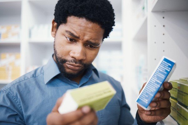 Man standing in a store aisle reading the label on a product box package